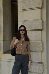a lady in a brown wool jacket and a pair of grey pants